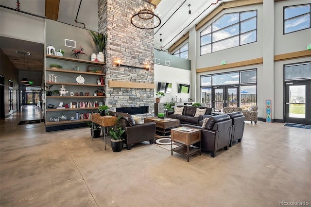 living room with a towering ceiling, a fireplace, visible vents, and concrete floors