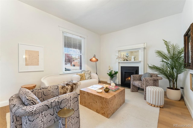 living area with baseboards, a fireplace with flush hearth, and light wood-style flooring