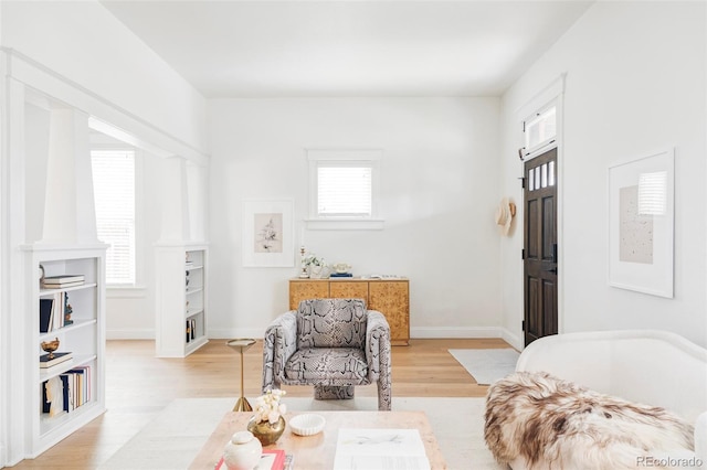 living area with light wood-type flooring and baseboards
