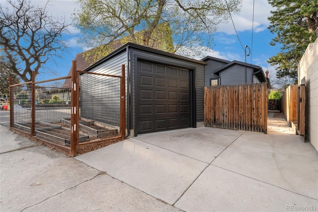 garage featuring fence, driveway, and a vegetable garden