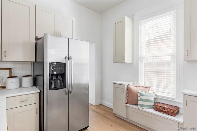 kitchen with stainless steel fridge, light wood-style flooring, a healthy amount of sunlight, and tasteful backsplash