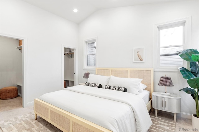 bedroom featuring baseboards, a walk in closet, lofted ceiling, and light carpet