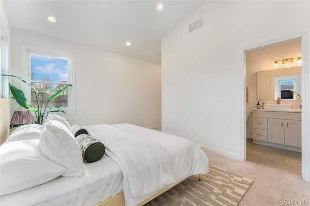 bedroom featuring ensuite bathroom, multiple windows, light carpet, and visible vents