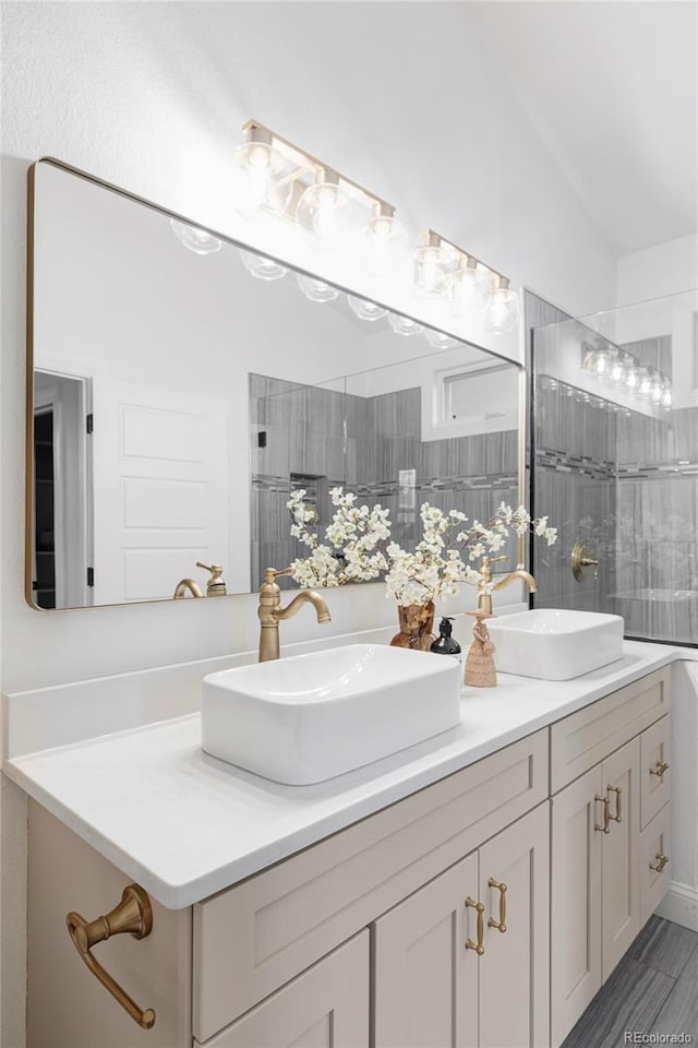 bathroom featuring double vanity, a sink, and a tile shower