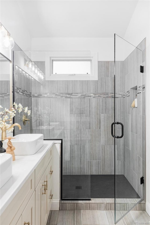 bathroom featuring a sink, a stall shower, and double vanity