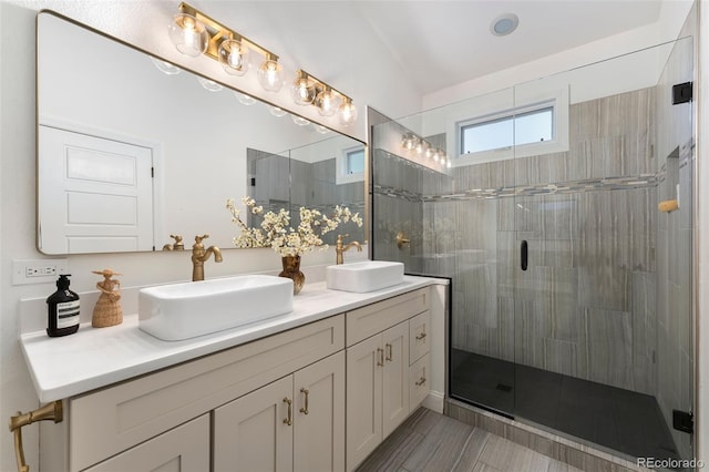 full bath with a sink, a stall shower, and double vanity