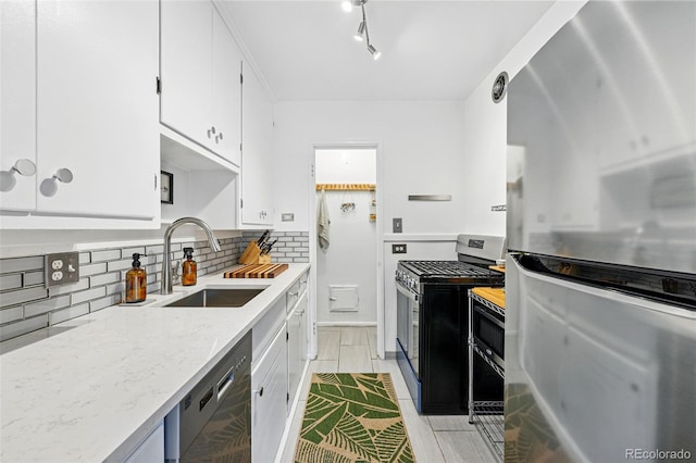 kitchen featuring light stone countertops, white cabinets, a sink, appliances with stainless steel finishes, and backsplash