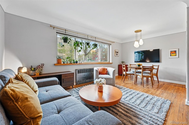 living room with radiator, baseboards, and light wood finished floors