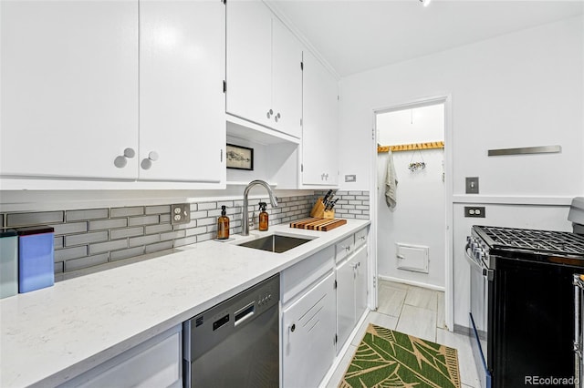 kitchen with appliances with stainless steel finishes, tasteful backsplash, a sink, light stone counters, and white cabinets