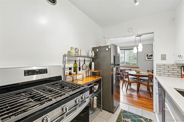 kitchen featuring light tile patterned floors, light stone counters, tasteful backsplash, and stainless steel appliances