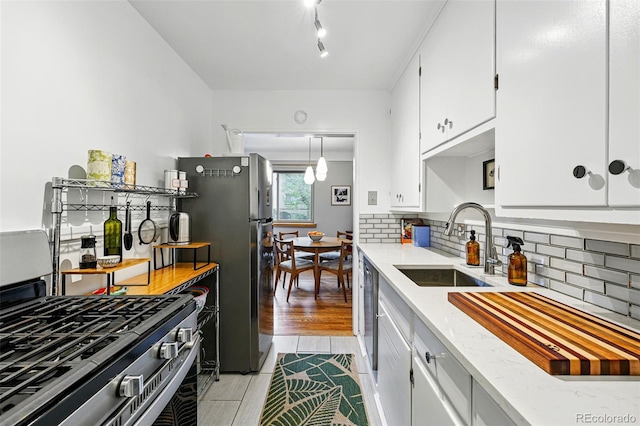 kitchen with decorative backsplash, stainless steel appliances, white cabinetry, and a sink