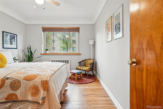 bedroom with baseboards, radiator heating unit, ceiling fan, and wood finished floors