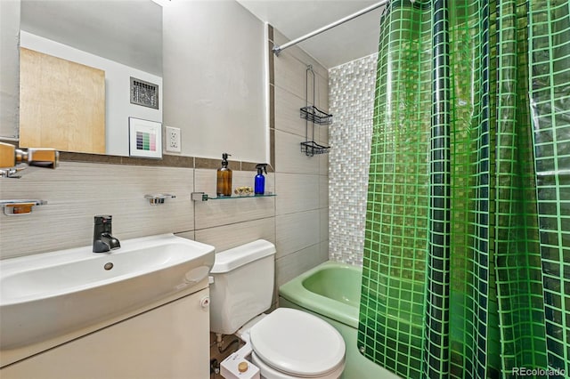 full bath featuring vanity, toilet, tile walls, and shower / tub combo with curtain