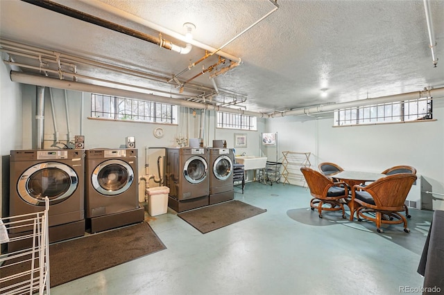 clothes washing area with a sink, a textured ceiling, and washer and dryer