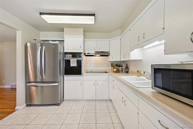 8250 Chase Way, Arvada, CO 80003 - kitchen with black appliances, under cabinet range hood, light countertops, tasteful backsplash, and white cabinets