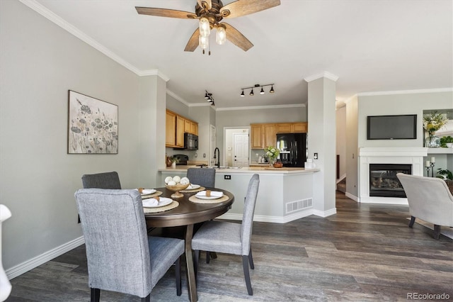 5193 E 119th Way, Thornton, CO 80233 - dining space featuring dark wood-style floors, a glass covered fireplace, ceiling fan, crown molding, and baseboards