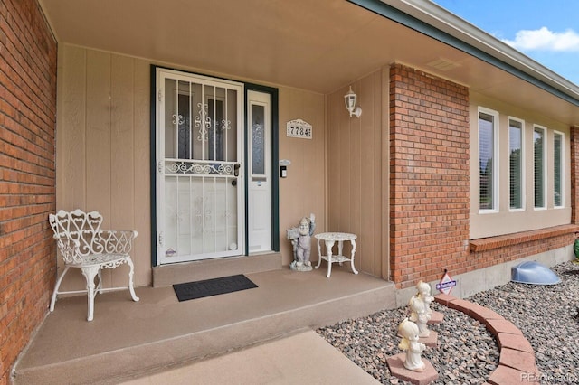 7784 Lewis St, Arvada, CO 80005 - doorway to property featuring brick siding and covered porch