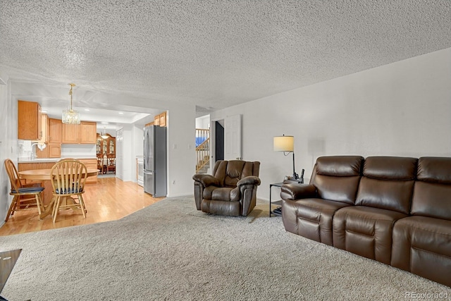 7784 Lewis St, Arvada, CO 80005 - living area with a chandelier, stairway, a textured ceiling, light colored carpet, and light wood-style floors
