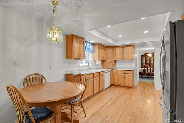 7784 Lewis St, Arvada, CO 80005 - kitchen featuring freestanding refrigerator, dishwasher, light wood-type flooring, a chandelier, and light countertops