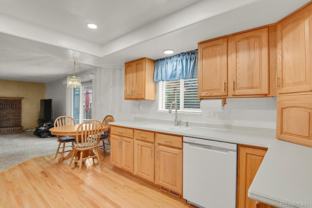 7784 Lewis St, Arvada, CO 80005 - kitchen featuring white dishwasher, light countertops, open floor plan, light wood-type flooring, and decorative backsplash