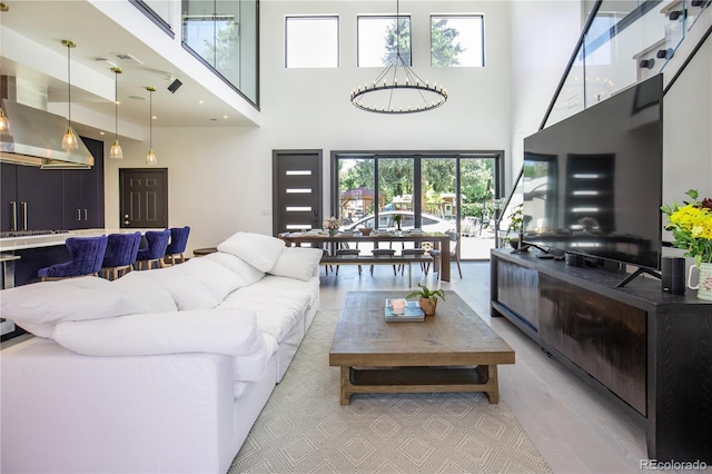 living room with light hardwood / wood-style floors, a healthy amount of sunlight, and a towering ceiling