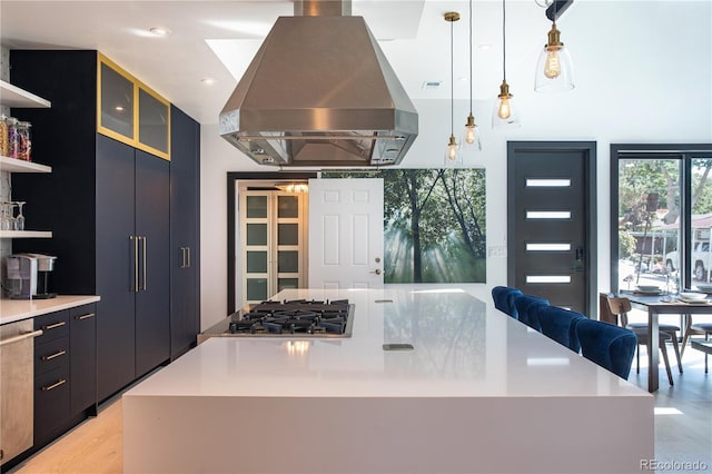 kitchen with a large island, hanging light fixtures, stainless steel gas cooktop, island range hood, and light wood-type flooring