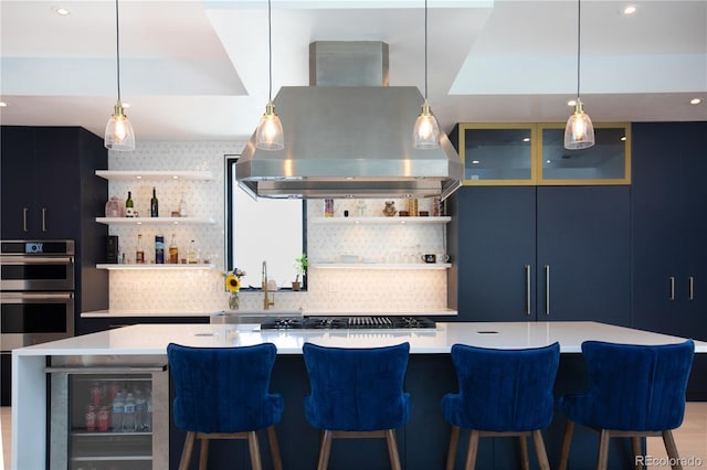 kitchen featuring island exhaust hood, decorative backsplash, beverage cooler, pendant lighting, and a large island