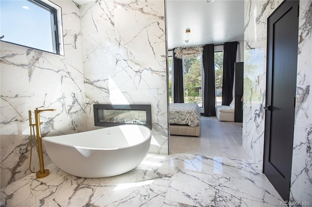 bathroom featuring a tub to relax in, a healthy amount of sunlight, and tile walls