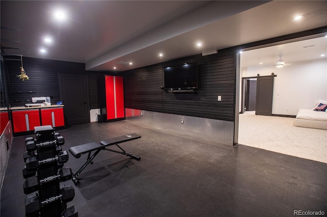 workout room with a barn door and ceiling fan