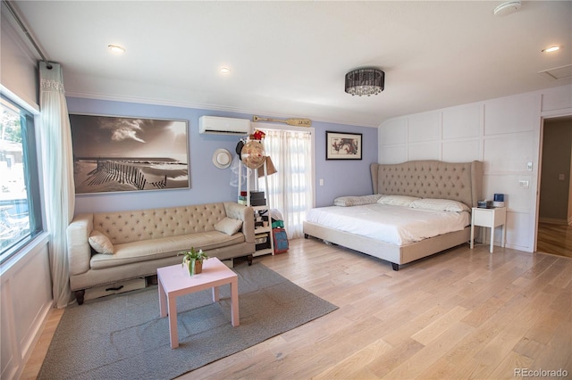 bedroom featuring light wood-type flooring, an AC wall unit, and ornamental molding