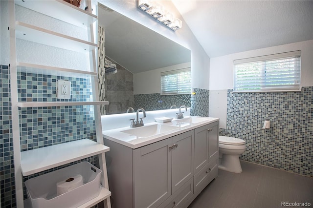 bathroom featuring vanity, toilet, tile walls, and lofted ceiling