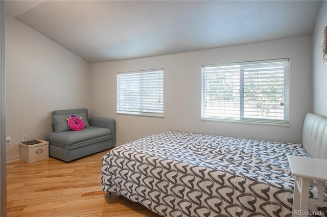 bedroom featuring multiple windows, light hardwood / wood-style flooring, and lofted ceiling