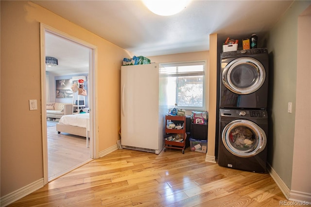 laundry area with light hardwood / wood-style floors and stacked washer and dryer