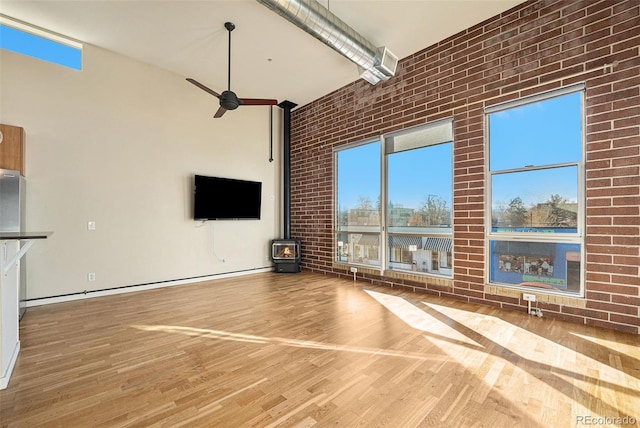 4258 Tennyson St Unit 104, Denver, CO 80212 - unfurnished living room with a wood stove, a ceiling fan, wood finished floors, a high ceiling, and plenty of natural light