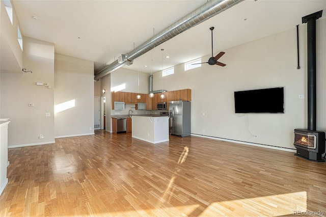 4258 Tennyson St Unit 104, Denver, CO 80212 - unfurnished living room with a wood stove, a towering ceiling, ceiling fan, and light wood-style flooring