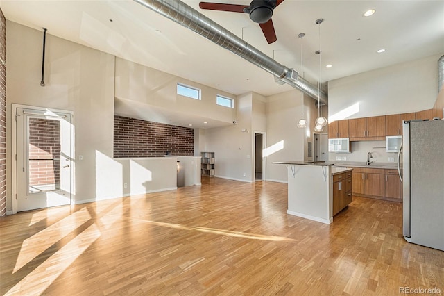 4258 Tennyson St Unit 104, Denver, CO 80212 - kitchen with freestanding refrigerator, a high ceiling, brown cabinets, open floor plan, and a ceiling fan