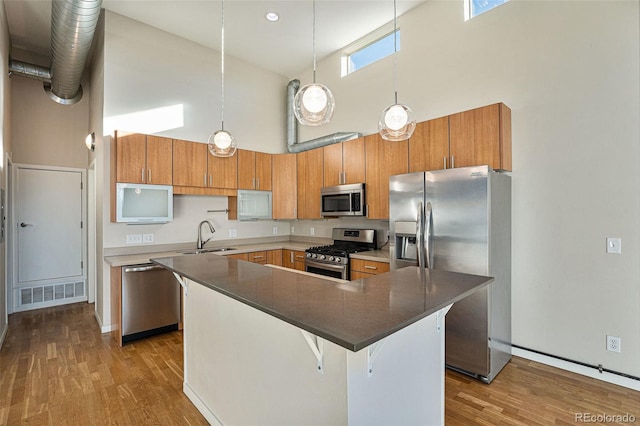 4258 Tennyson St Unit 104, Denver, CO 80212 - kitchen with appliances with stainless steel finishes, high vaulted ceiling, wood finished floors, and brown cabinetry
