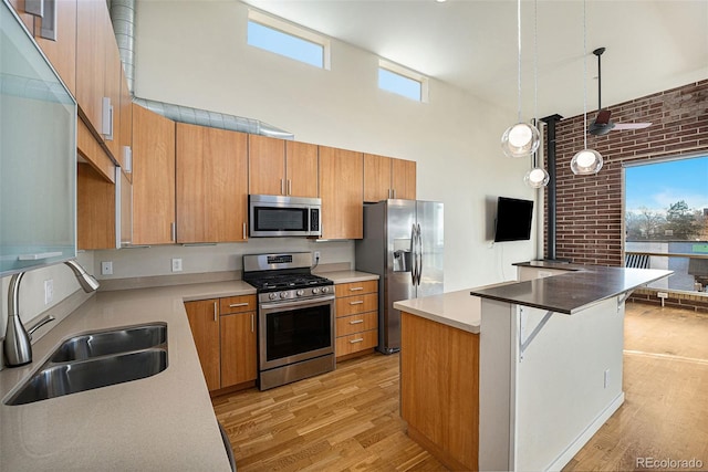 4258 Tennyson St Unit 104, Denver, CO 80212 - kitchen featuring appliances with stainless steel finishes, a towering ceiling, light wood finished floors, brown cabinets, and pendant lighting