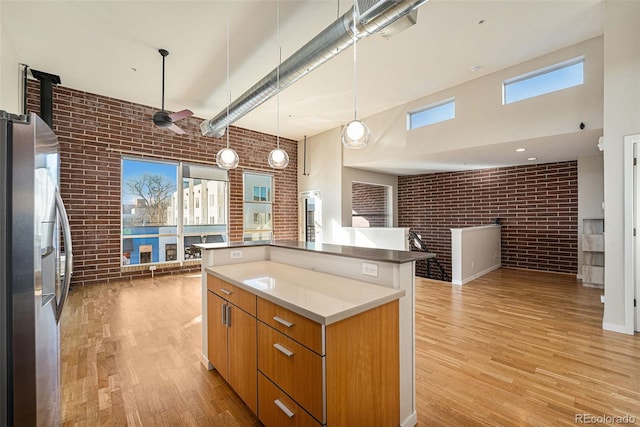 4258 Tennyson St Unit 104, Denver, CO 80212 - kitchen featuring brick wall, stainless steel fridge with ice dispenser, a high ceiling, light wood-style floors, and brown cabinets