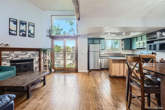 10806 W Evans Ave Unit 5, Lakewood, CO 80227 - kitchen featuring appliances with stainless steel finishes, green cabinets, a sink, wood-type flooring, and a stone fireplace