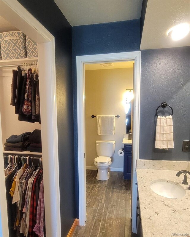 10806 W Evans Ave Unit 5, Lakewood, CO 80227 - bathroom with vanity, a walk in closet, toilet, wood finished floors, and baseboards