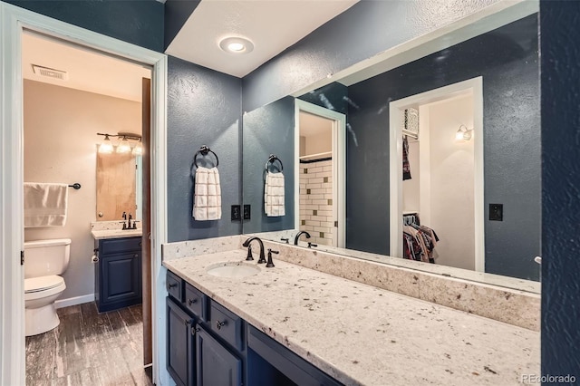 10806 W Evans Ave Unit 5, Lakewood, CO 80227 - bathroom featuring toilet, a spacious closet, a textured wall, vanity, and wood finished floors