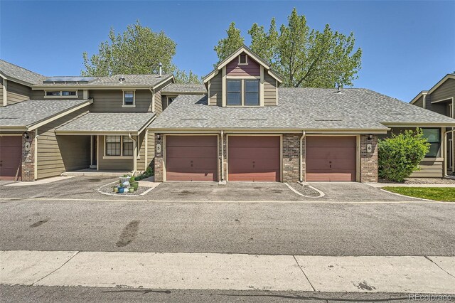 10806 W Evans Ave Unit 5, Lakewood, CO 80227 - view of front facade with roof mounted solar panels, roof with shingles, asphalt driveway, and brick siding