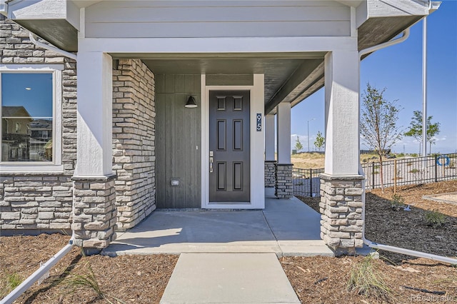 95 N Vandriver Pl, Aurora, CO 80018 - property entrance with stone siding, fence, and a porch