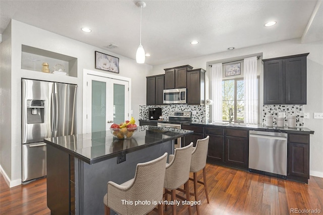 4873 Cathay Ct, Denver, CO 80249 - kitchen featuring stainless steel appliances, dark countertops, a sink, dark wood-style flooring, and recessed lighting