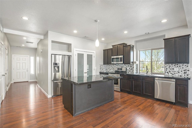 4873 Cathay Ct, Denver, CO 80249 - kitchen featuring stainless steel appliances, dark countertops, a sink, dark wood finished floors, and a textured ceiling
