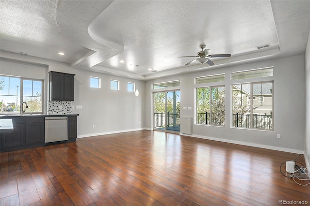 4873 Cathay Ct, Denver, CO 80249 - unfurnished living room featuring a tray ceiling, a textured ceiling, dark wood-style floors, ceiling fan, and baseboards