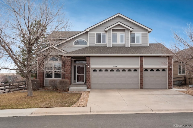 traditional-style home with a shingled roof, fence, concrete driveway, and brick siding