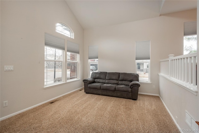 carpeted living area featuring high vaulted ceiling, visible vents, and baseboards