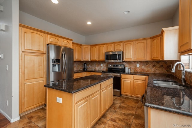 kitchen with a sink, appliances with stainless steel finishes, a center island, dark stone counters, and tasteful backsplash